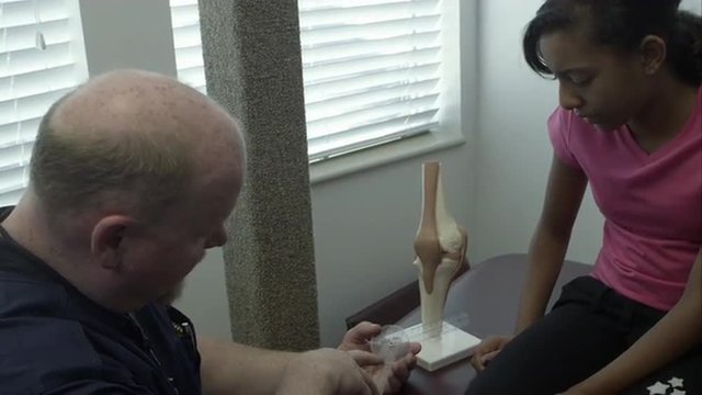Therapist explaining joint protractor to teenage girl.