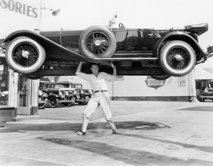 Strong man lifting a car over his head 