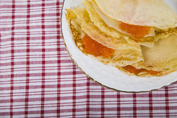 Delicious pancakes with red caviar on a table