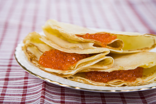 Delicious pancakes with red caviar on a table