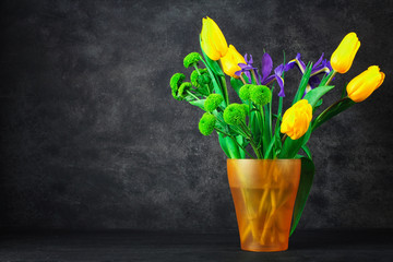beautiful iris with tulips and green chrysanthemums in a vase on dark background dark wooden table
