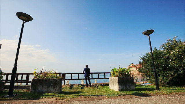 Stylish groom enjoying beautiful seascape and clear blue sky in  Montenegro, Budva