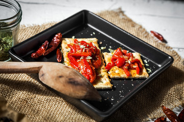 Cracker with roasted peppers, chili pepper and oregano