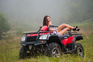 Beautiful girl sitting on four-wheeler ATV. Wearing high heels smiling and looking towards the camera