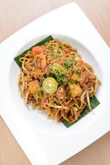 Asian style spicy fried noodles, ready to serve on dining table.