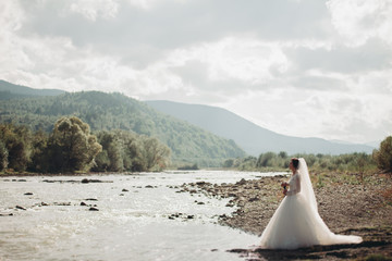 Girl, model, bride on a background of the river and mountains. Beauty portrait 