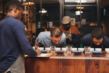 Barista training with rows of different coffees in roastery