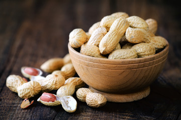 Peanuts in a bowl on dark rustic wooden background. Shallow DOF with copy space for your text