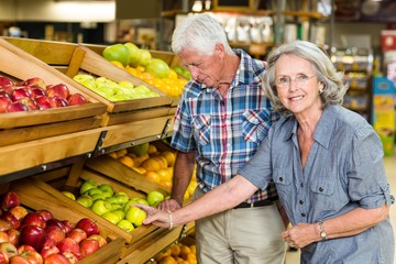 Smiling senior couple buying apples