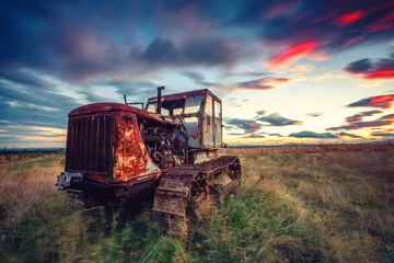 Fototapeten Beautiful sunset over field and old rusty tractor © ValentinValkov