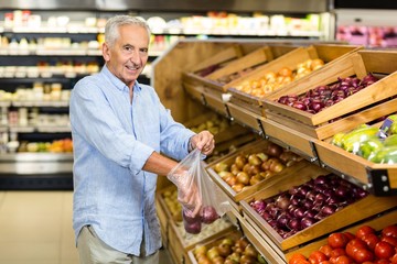 Smiling senior man buying red onions at the grocery shop © WavebreakmediaMicro