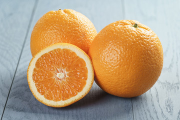 ripe oranges with half sliced on blue wood table, shallow focus