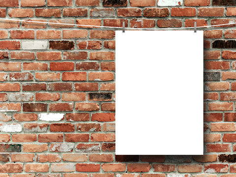 Close-up of one hanged paper sheet with pegs on red and brown brick wall background