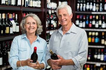 Smiling senior couple choosing wine at the supermarket