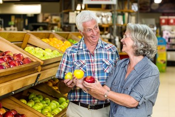 Smiling senior couple holding apples
