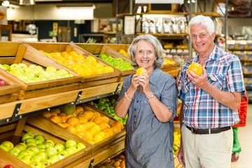 Smiling senior couple holding oranges