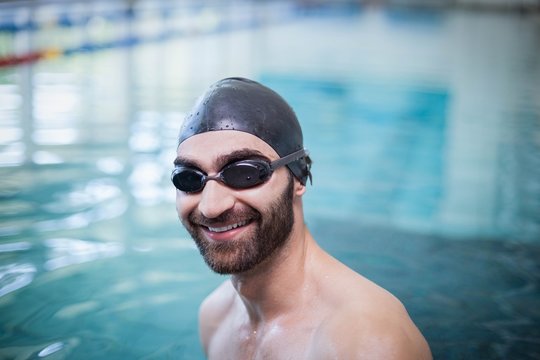 Smiling man wearing swim cap and goggles - Powered by Adobe