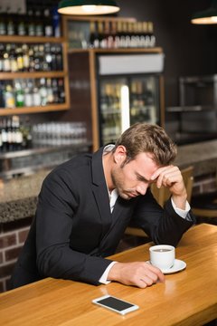 Handsome man looking at smartphone and having a coffee