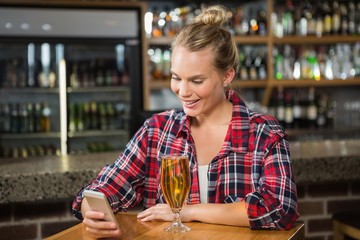 Pretty woman using smartphone and having a beer