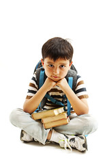 Schoolboy bored, frustrated and overwhelmed by studying homework. Little boy sitting down on floor isolated on white background