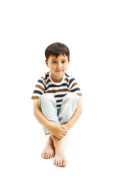 
A young boy sitting on the floor. Isolated on white background