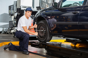 Fototapeta na wymiar Confident Mechanic Fixing Car Tire