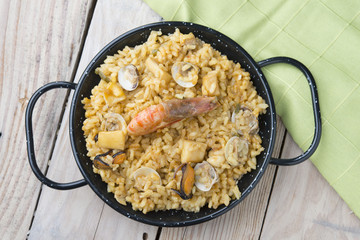 Vegetable paella with seafood on a wooden background