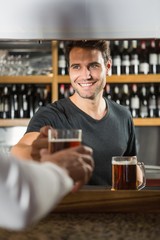 Handsome bar tender giving a pint to customer