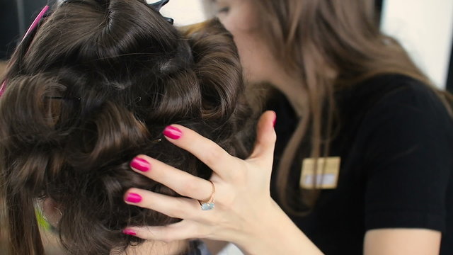 Hair stylist making curls on customer hair using electric curler