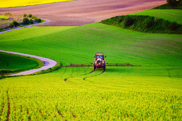 Farm machinery spraying insecticide to the green field, agricultural natural seasonal spring background