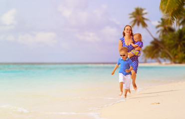 Naklejka premium happy little boy with mother and sister running on beach