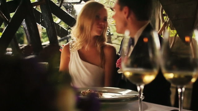 Wedding couple drinking foaming champagne and softly kissing in old cafe close up