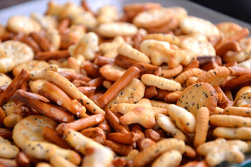 A pile of crackers, potato chips and sticks in a bowl