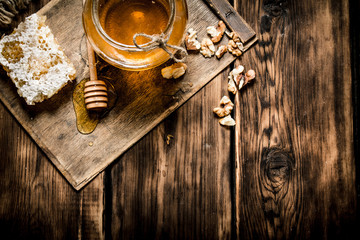 Sweet honey in the comb, glass jar with nuts.