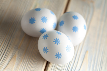 Three white Easter eggs on wooden board