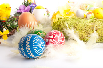 Easter decoration with painted eggs, flowers, feathers and chick. Colorful Easter eggs  in decorative wreath.