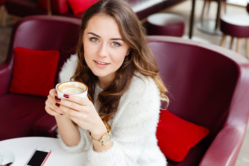 Girl with brown curly hair sitting in cafe