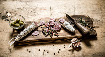 Spicy salami with spices, rosemary and olives on the Board.