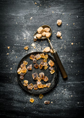 Brown cane sugar. On black rustic background.