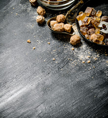 Brown cane sugar. On black rustic background.