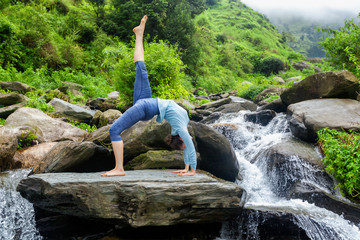 Woman doing yoga asana at waterfall
