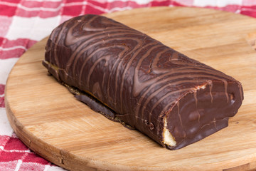 Chocolate roll cake on the kitchen wooden board