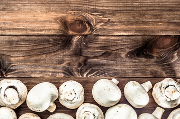 Whole mushrooms champignons on rustic wooden background.