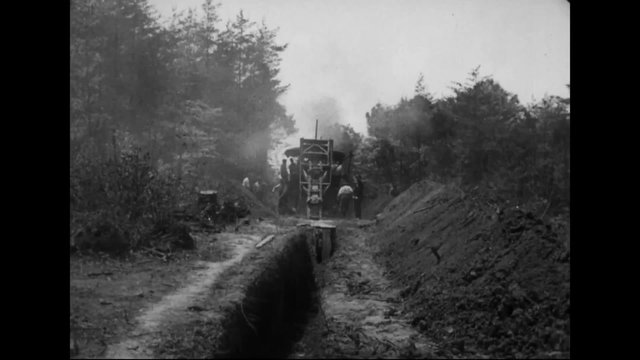 1914 steam shovels dig a road or railroad through a rural area using heavy manual labor.