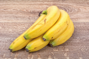 A clump of yellow bananas on a wooden background