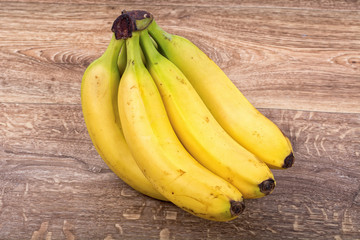 A clump of yellow bananas on a wooden background