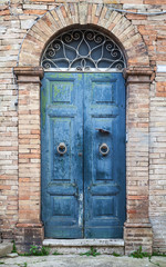 Blaue Holztür mit Bogen in alter Backsteinmauer