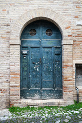 Blue wooden door with arch in old stone wall