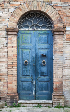 Blue wooden door with arch in old brick wall