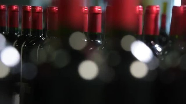 Wine bottles moving along a conveyor belt in a wine bottling factory.